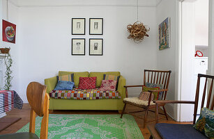 Living room with green sofa, colourful cushions, green carpet and vintage furniture