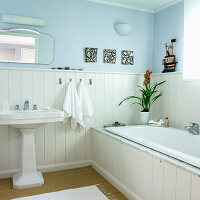 Country-style bathroom with light blue walls and white wooden elements