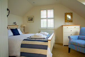 Brightly furnished bedroom with striped ceiling and striped armchair