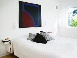 Modern bedroom with large abstract painting and patterned throw pillows