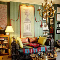 Wohnzimmer mit grüner Streifentapete, antiken Möbeln und bunten Textilien