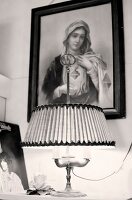 Religious picture hangs above bedside table with lamp