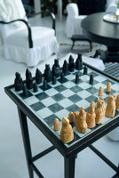 Chessboard with carved figures on side table in living room