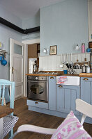 Country-style kitchen with light blue cupboards and traditional utensils