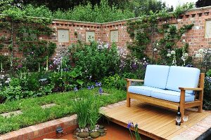 Üppig begrünter Garten mit hoher Gartenmauer, Gartenteich & Sitzecke am Teich mit Bank