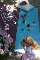 Girl plays with natural materials on yoga mats in the garden