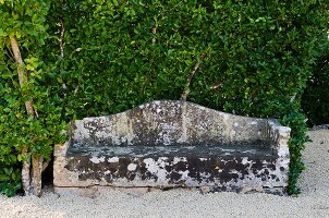 Weathered stone bench on gravel in garden