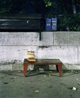 Stack of books on vintage metal coffee table in front of simple stone wall