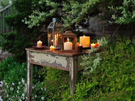 Brennende Kerzen & Laternen auf Tisch im Garten