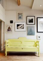 Gelbe Vintage-Holzbank vor einer zeitgenössischen Bilderwand