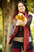 Young woman holding autumn leaves