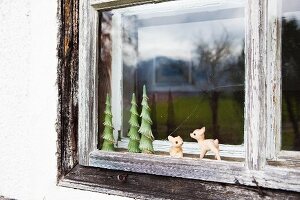 Altes Holzfenster mit kleinen Figuren an einem Bauernhaus