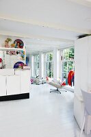 Open-plan, white interior with various colourful accessories