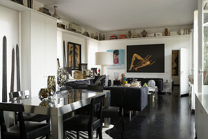 Open-plan living and dining area with sofa, table, artwork and shelves with decorations