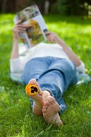 Woman lying on lawn reading magazine