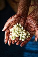 Indische Mehndi Hände (Kunstvolle Körperbemalung mit Henna) halten Jasminblüten