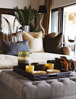 Tray with bowls on upholstered ottoman, sofa with throw pillows in the background