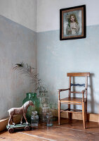 Corner with vintage wooden chair, glass vases and wooden horse on wheels