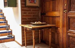 Holztisch mit Deko-Steinen nahe einer Treppe mit Backsteinwand