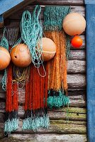 Nets and fishing buoys hanging on weathered wooden wall