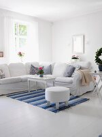 White living room with large corner sofa & blue and white rug