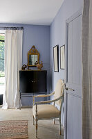 Historischer Stuhl an blau-grauer Wand neben Tür