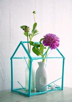 Stillleben mit zwei Vasen und Dahlien in türkisfarbenem Häuschenmodell