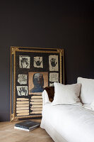 White couch and abstract artwork in a gold frame in a room with dark walls