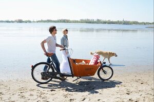 Man and dog with bicycle on their way to beach picnic