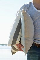 Man on beach holding two cushions