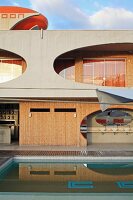 Hotel Cocoon in Salvador, Bahia, Brazil with oval apertures in concrete facade, wood panelling and pool in foreground