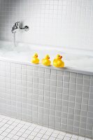 A bubble bath with rubber ducks on side of tub