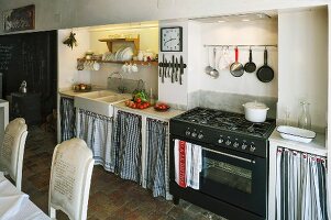 Schlichte Küchenzeile mit Vorhang an Unterschränken neben Gasherd