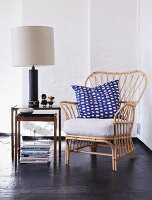 Cane armchair with cushions on table lamp on side talbe
