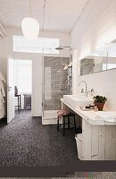 Selbstgebauter Waschtisch aus hellem Holz und Marmorkieselboden im Badezimmer einer Loftwohnung; Duschkabine mit Regendusche im Hintergrund