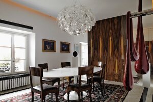 Bright dining room with white designer dining chairs, gilt-framed oil paintings and modern artworks