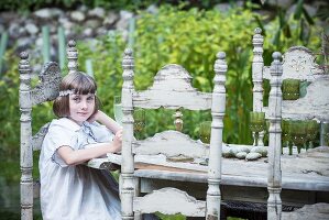 Girl sitting at white wooden table in garden