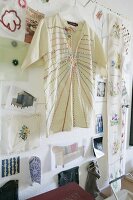 Embroidered shirt on coat hanger hung on wall in front of pictures