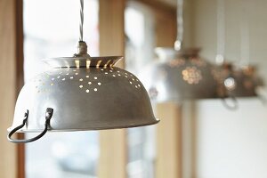 Vier Metallküchensiebe als Lampenschirme für Hängelampen