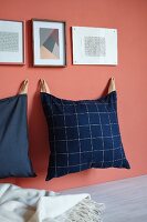 Hand-sewn cushions hung on pink wall from leather straps