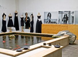 Large fish pond and elegant black clothing on tailors' dummies in couture studio