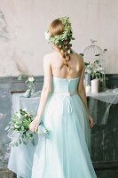 Fairy-tale bride holding bouquet and wearing flower wreath in vintage interior