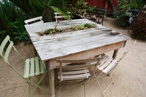 Miniature bed of succulents integrated into rustic wooden table outdoors