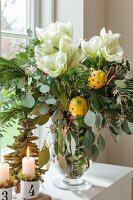 Weihnachtlicher Blumenstrauss mit weisser Amaryllis und gespickten Zitronen in Glasvase
