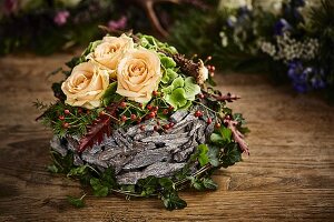Rosengesteck im alpinen Stil mit cremeweissen Rosen und Holzrinde