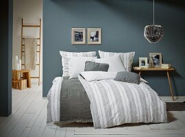 Skandinavisches Schlafzimmer mit gestreifter Bettwäsche und zweibeinigem Nachttisch