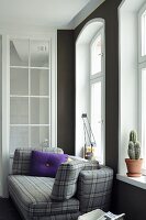 Purple scatter cushion on grey tartan sofa below arched window