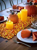 Gedeckter Tisch für Halloween dekoriert mit Kürbissen, Kerzen und Candy Corn