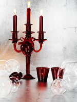 Red glass candelabra and baubles against silver wall