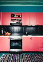Renovated kitchen with red cupboards and black-tiled splashback